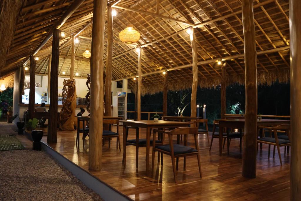un ristorante con tavoli e sedie in legno e un soffitto di Omkara Rekawa a Tangalle