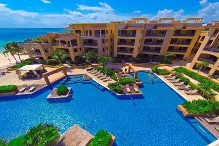 a resort with a large swimming pool next to the beach at Oceanfront Condo a Block Off 5th in Heart of Playa in Playa del Carmen