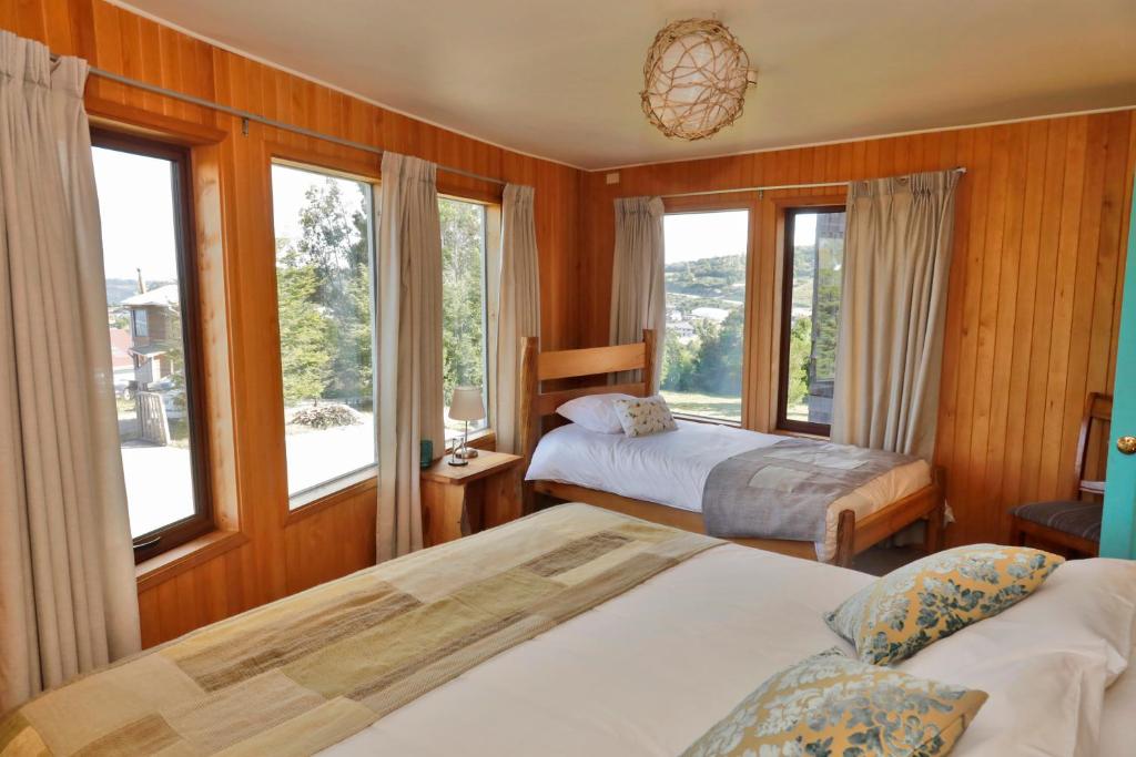 a bedroom with two beds and windows with a view at Lodge Cumbres de Chiloe in Castro