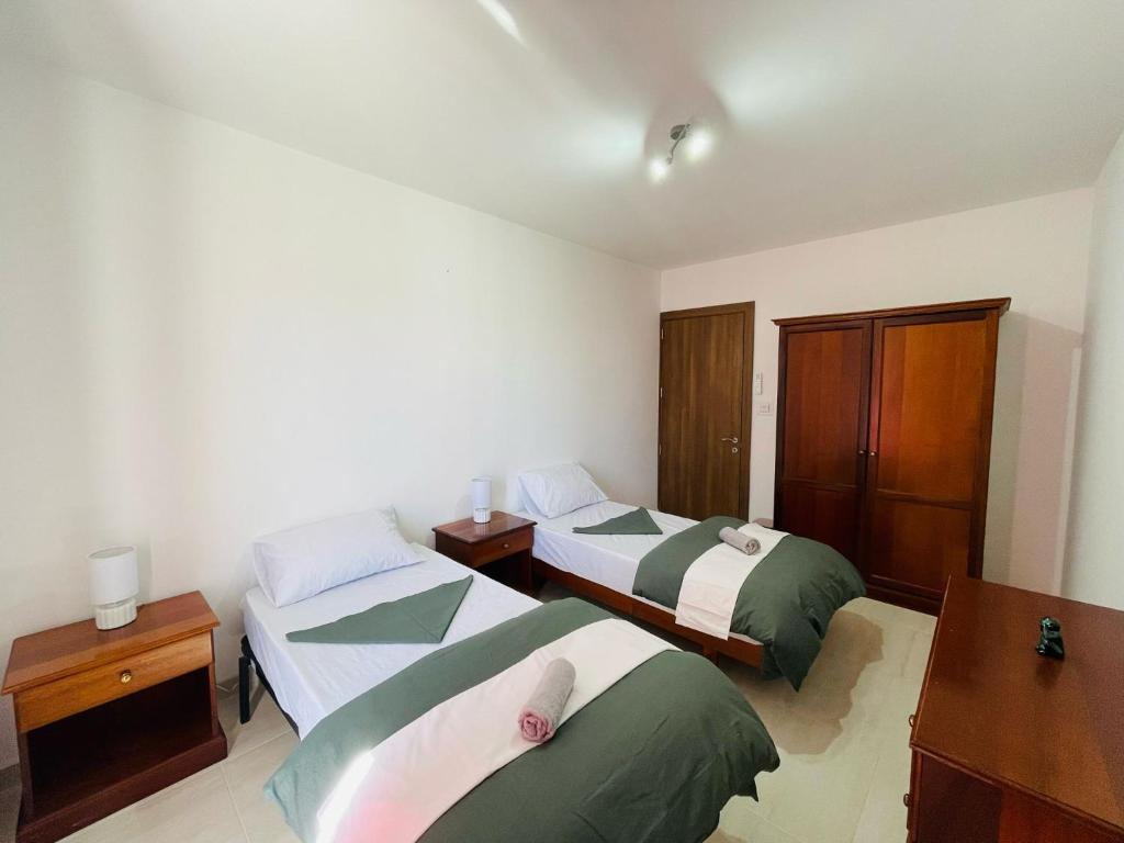 a bedroom with two beds and a desk and cabinets at Coral Cove Comfort Room 2 in St Paul's Bay