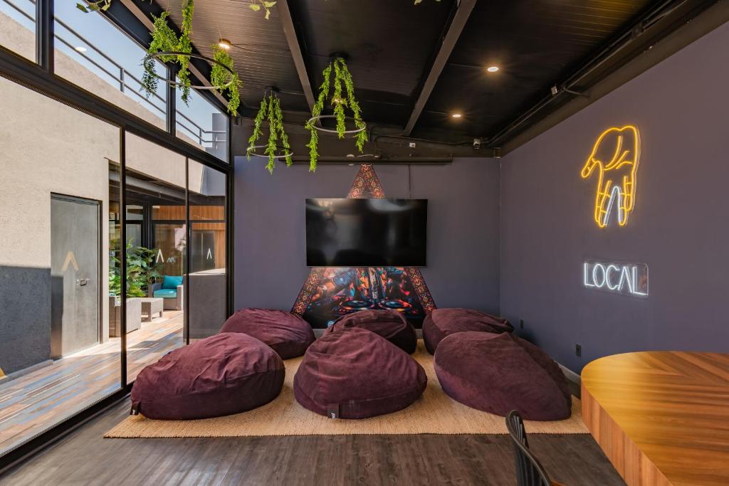 A relaxed lounge with purple bean bags, a television and a neon sign.