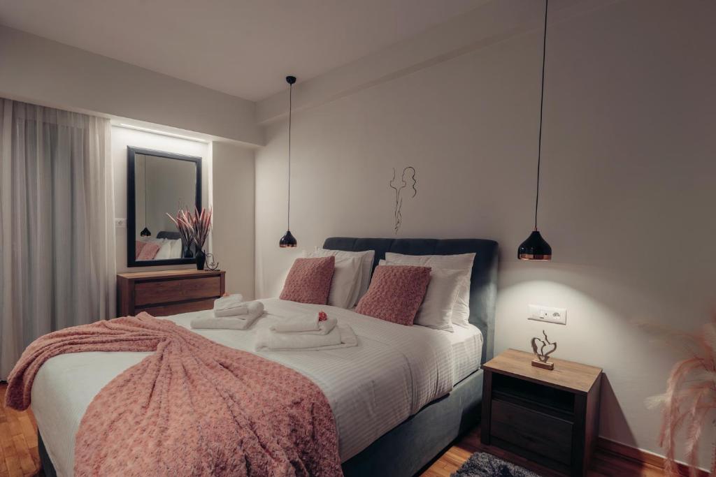 una camera da letto con un grande letto bianco con cuscini rosa di Vivian's Deluxe Apartment a Patra