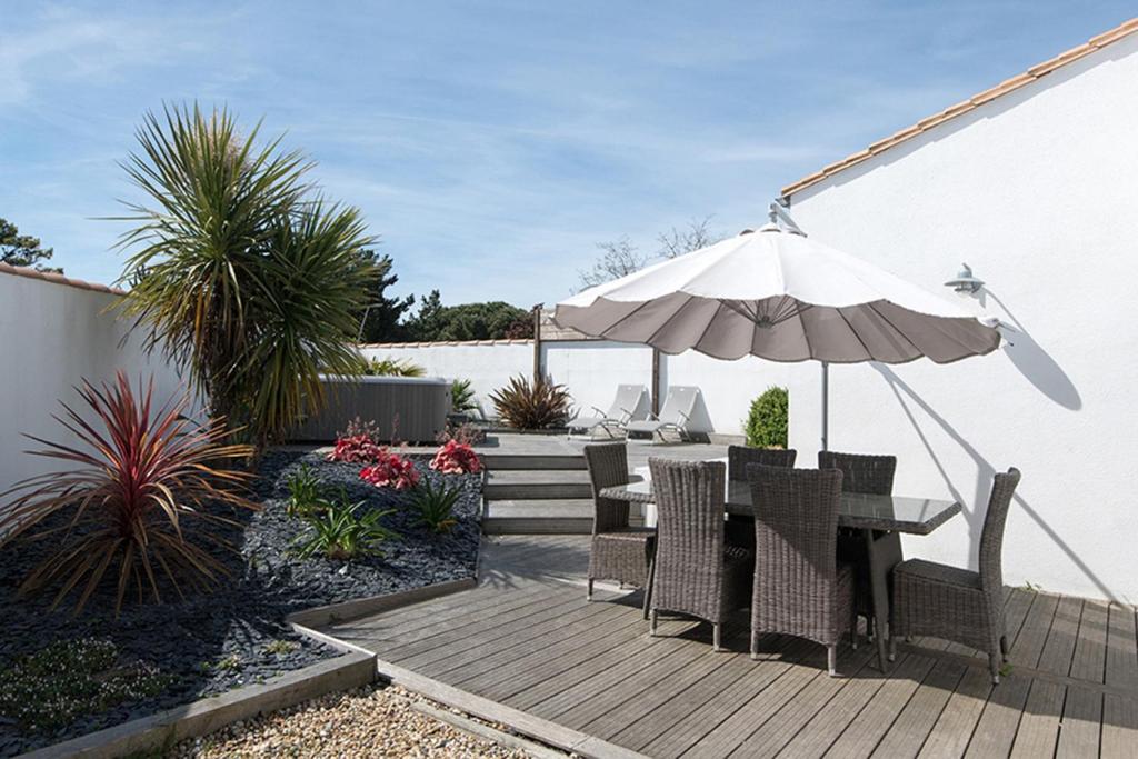 a patio with a table and an umbrella at Villa Odys in Rivedoux-Plage