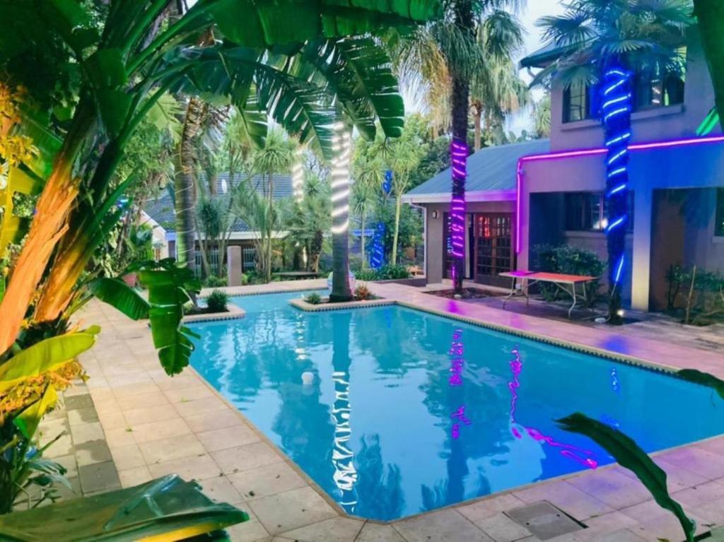 a pool in front of a house with palm trees at GSpot94 in Johannesburg