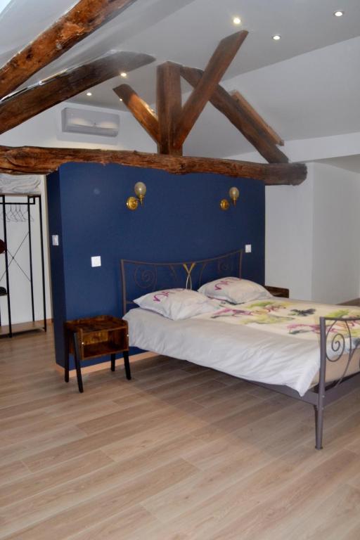 une chambre avec un lit avec un mur bleu dans l'établissement Les Gîtes de Monthermé L'Appartement belvédère sur Monthermé, à Monthermé