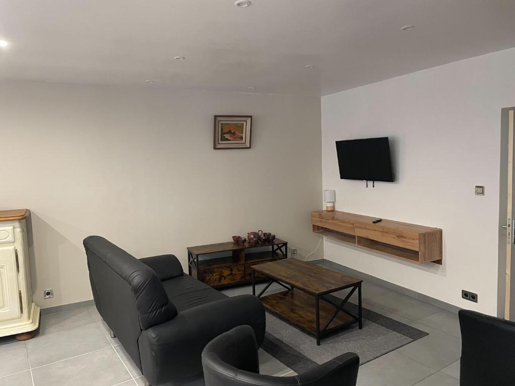 sala de estar con sofá y TV en la pared en Appartement du Pont Monthermé en Monthermé