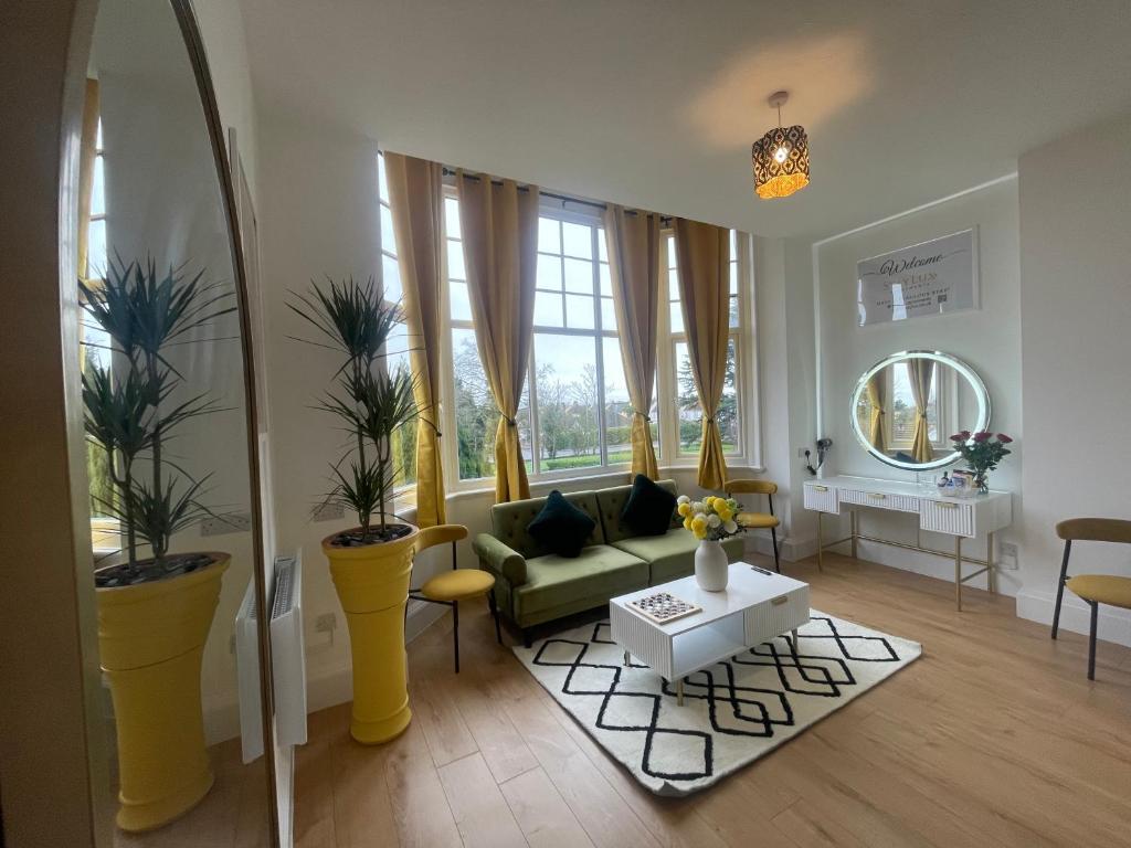 uma sala de estar com um sofá verde e janelas em Clacton Chic em Clacton-on-Sea
