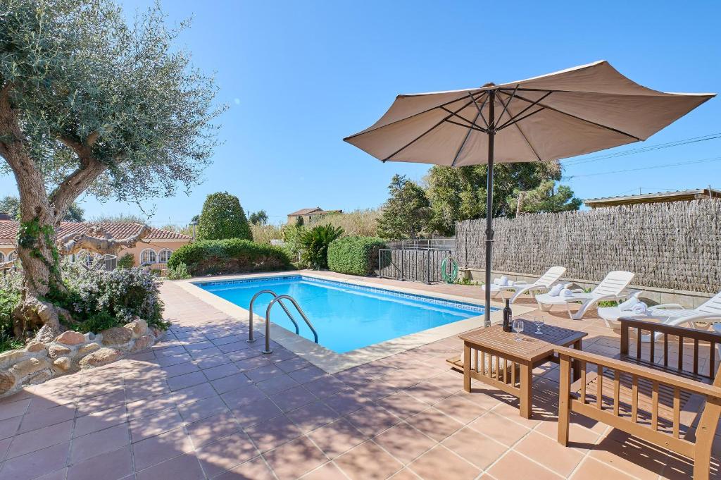a pool with a table and an umbrella and chairs at Villa Franci - Blanes in Blanes