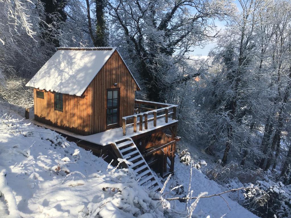 een kleine hut met een met sneeuw bedekt dak in het bos bij Cabane du Voyageur in Yvoir