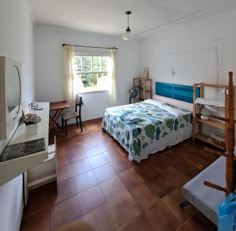 1 dormitorio con cama, escritorio y ventana en Casa Pé na Areia Cantão do Bora Bora - Manaaki Surf Hostel, en São Sebastião
