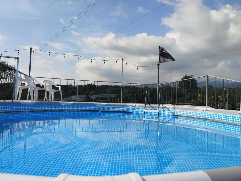 una gran piscina con 2 sillas y una bandera en Dreamcatcher House Bus Experience 2 en Sarchí