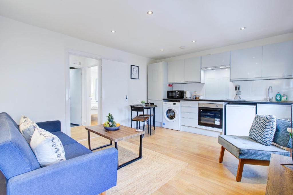 a living room with a blue couch and a kitchen at Wonderful Two-Bedroom Apartment in London