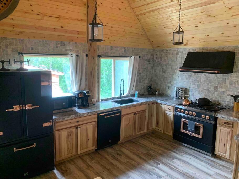 a kitchen with black appliances and a wooden ceiling at Brother Bear Lodge at Talkeetna in Talkeetna