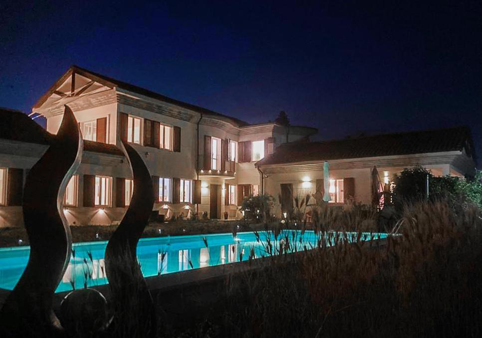 una casa grande con piscina por la noche en Villa Bricco Astiani, en Montegrosso dʼAsti
