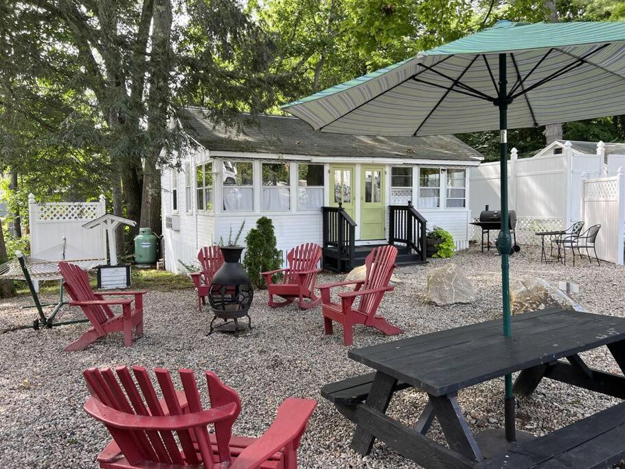 a picnic table with red chairs and an umbrella at Cottage 8-9 - Stand Alone 2 Bedroom / 2 Bath in Wolfeboro