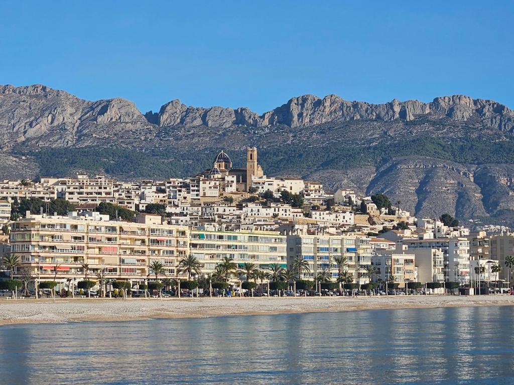 a large building on the beach with mountains in the background at HOSTAL LUXURY NIT I DIA in Altea