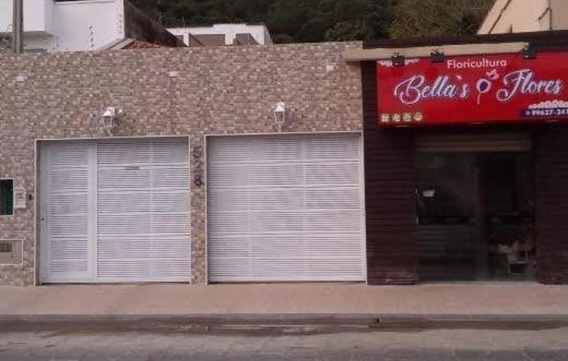 a building with three garage doors on a street at Casa Praia Temporada Itanhaém in Itanhaém
