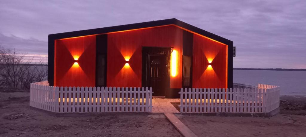 un pequeño edificio con luces naranjas a un lado del agua en Casuta camping BenBeach 
