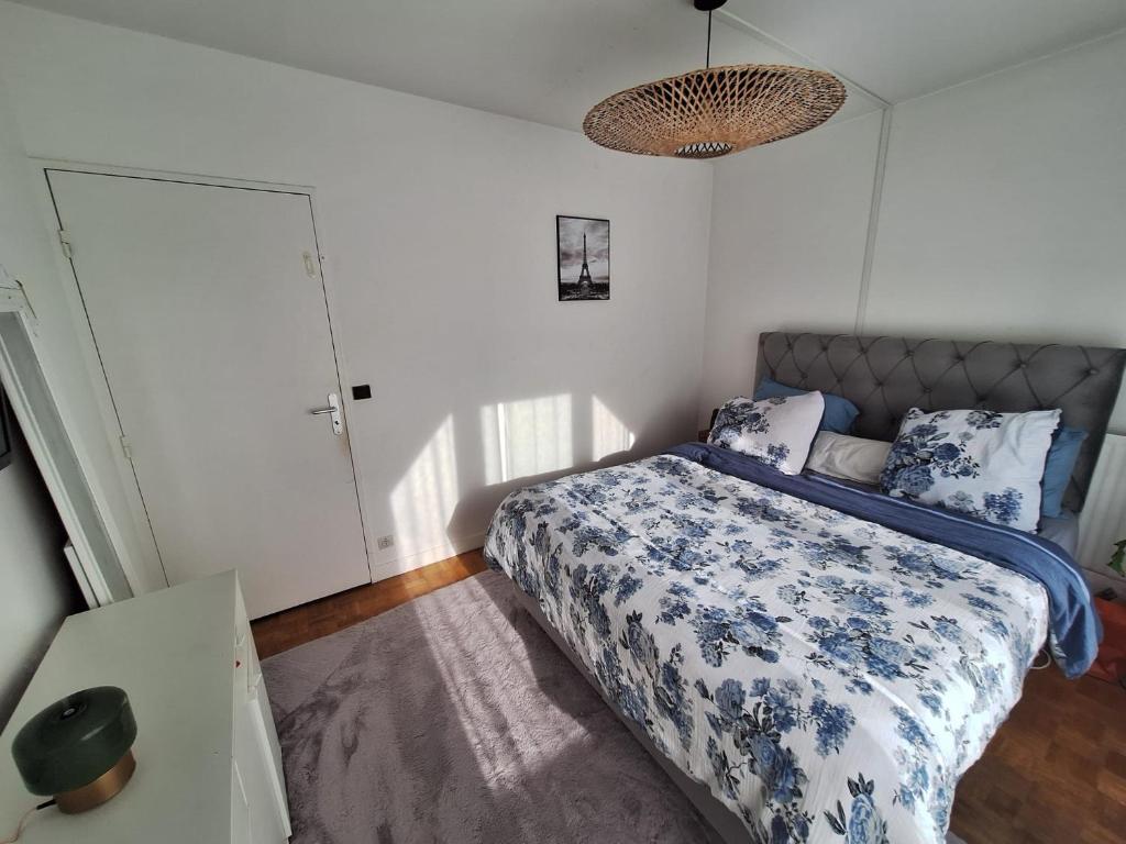 a bedroom with a bed with a blue and white comforter at MERVEILLE APP in Suresnes