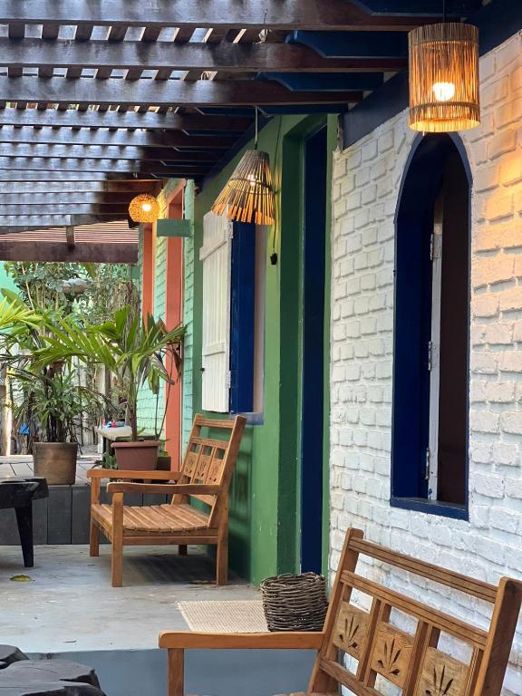 a patio with two wooden chairs and a building at Casa deck Caraíva in Caraíva