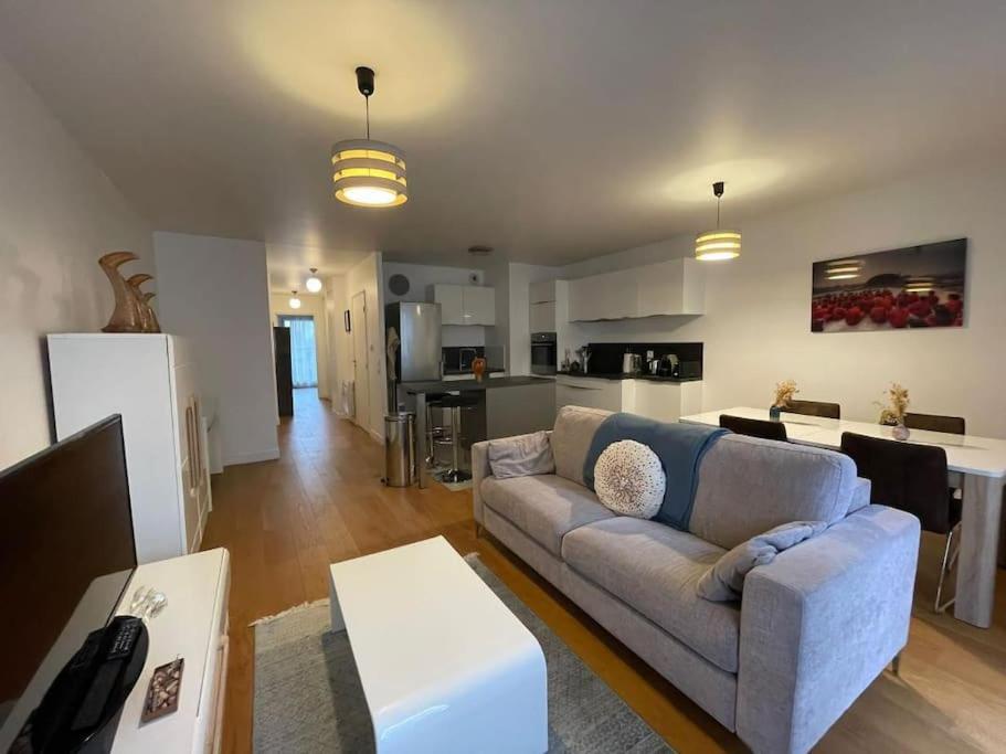 ein Wohnzimmer mit einem Sofa und einer Küche in der Unterkunft Appartement 2 pièces 57m2 Terrasse sur cour Proche Paris Porte Maillot in Levallois-Perret
