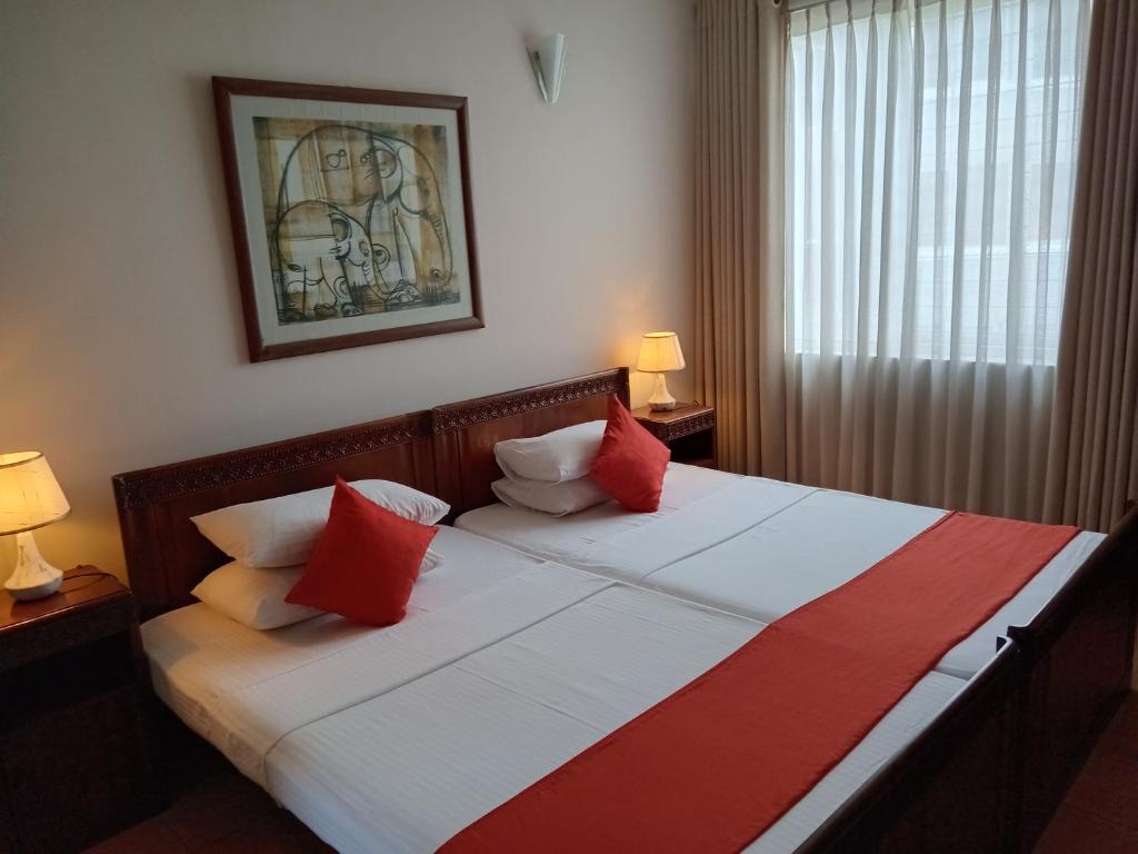 - une chambre dotée d'un grand lit avec des oreillers rouges et blancs dans l'établissement Rockwood Apartment Colombo 7, à Colombo