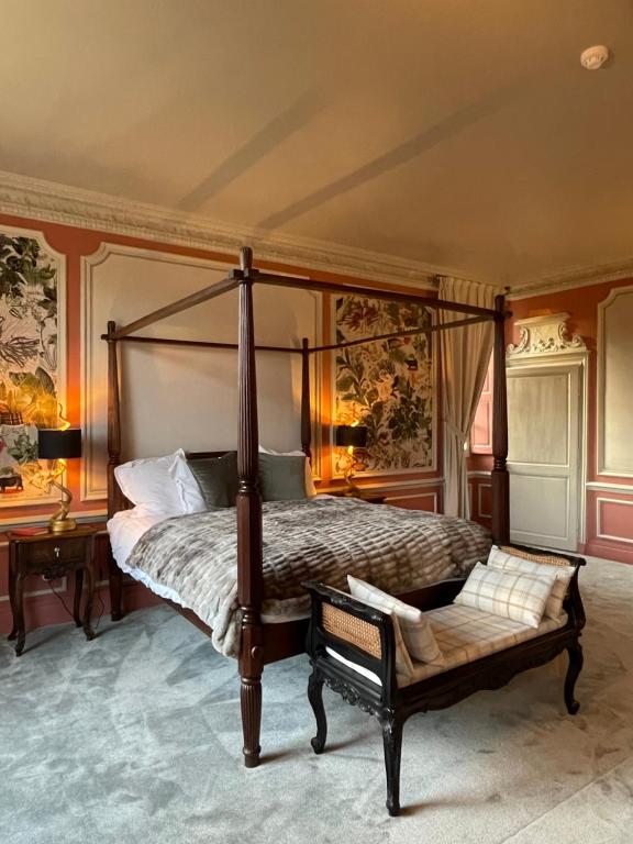 a bedroom with a canopy bed and a bench at Château de la Huberdière in Nazelles