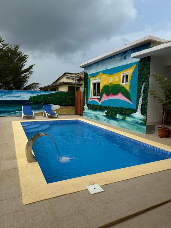a swimming pool in front of a house with a mural at Paradise Agua Leve Residential in São Tomé