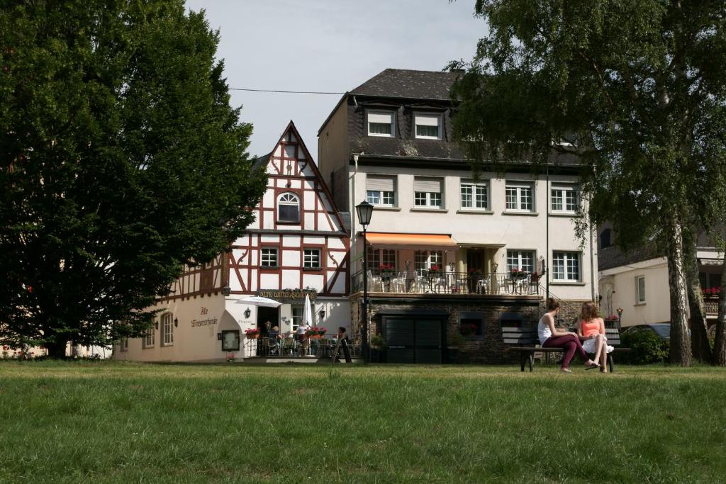 a woman sitting on a bench in front of a house at Alte Winzerschenke in Bruttig-Fankel