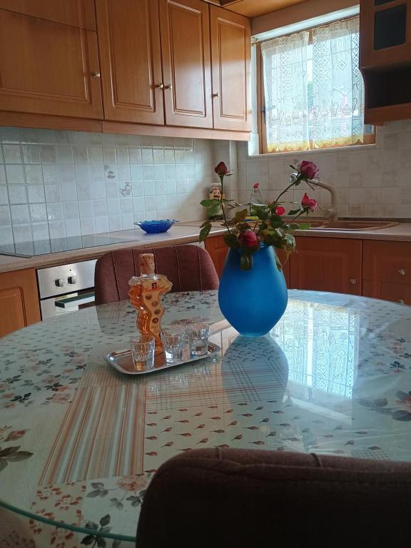 een keukentafel met een blauwe vaas met bloemen erop bij ENJOY APARTMENT in Ovriá