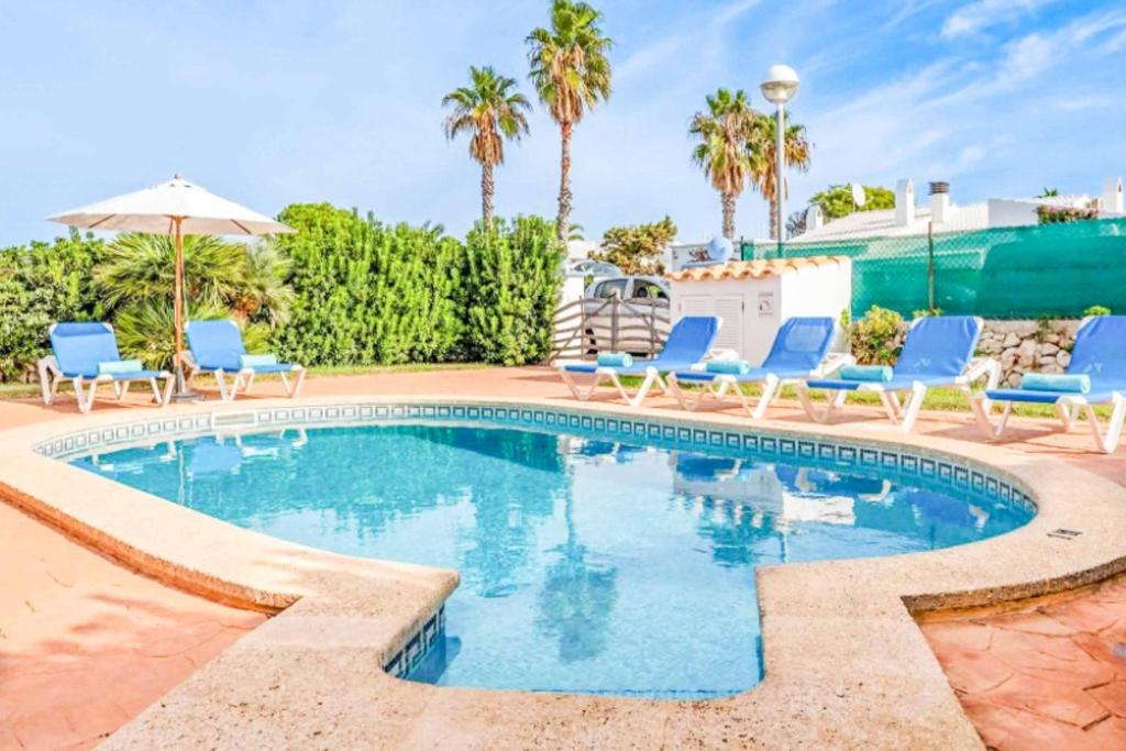 - une piscine avec des chaises bleues et des palmiers dans l'établissement Son Fonoll, à Cala'n Bosch
