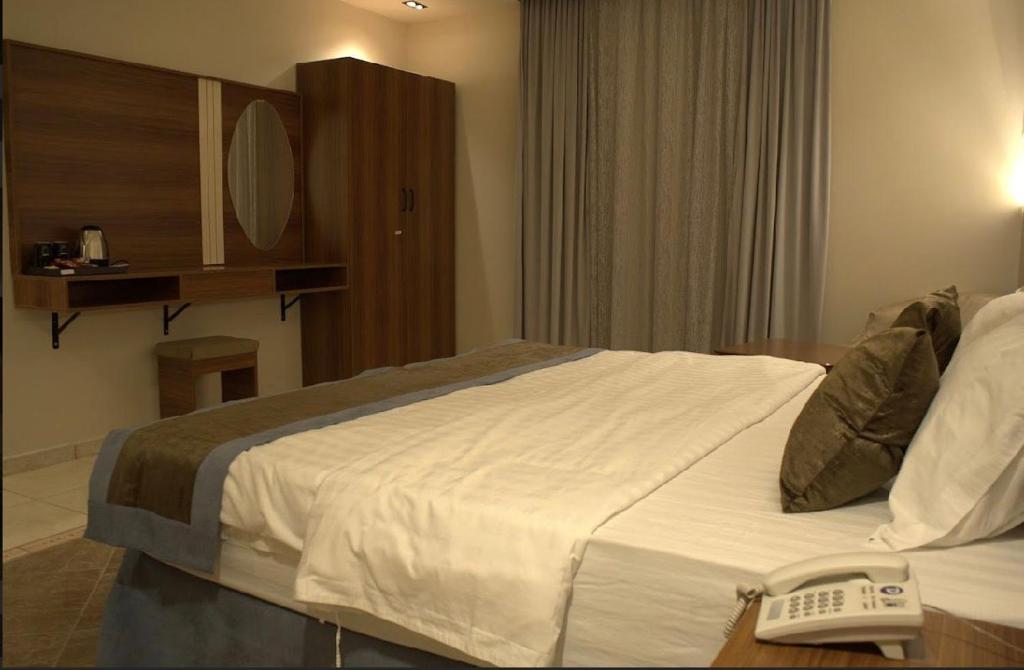 pokój hotelowy z łóżkiem z telefonem na stole w obiekcie Dosh Hotel w Medynie