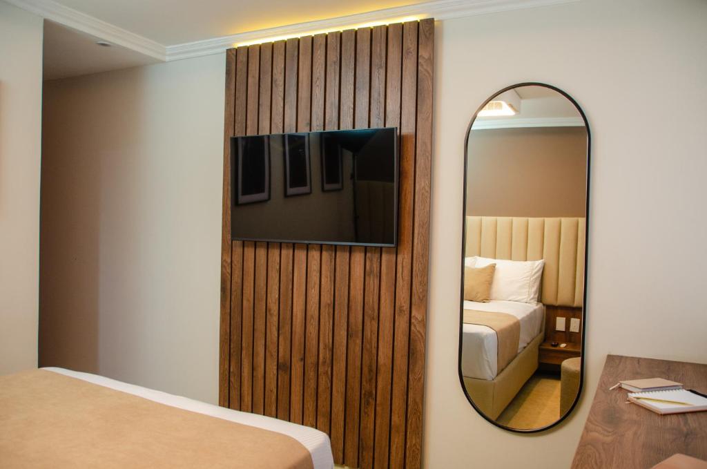 a hotel room with a mirror and a bed at Hotel ByHours Las Américas in Bogotá