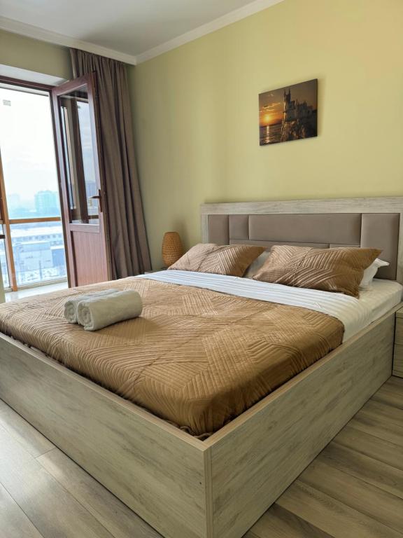 a large bed in a bedroom with a large window at VIP apartments arbat mega in Almaty