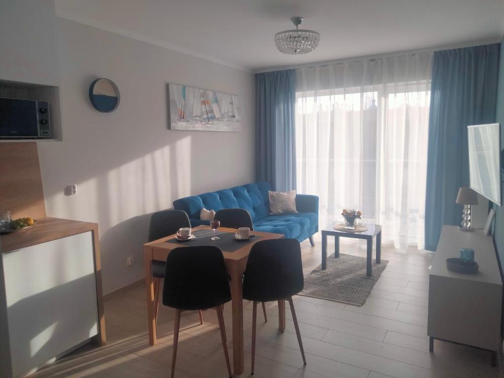 a living room with a blue couch and a table at Apartament Nawigator Rybacka 12 b in Kołobrzeg