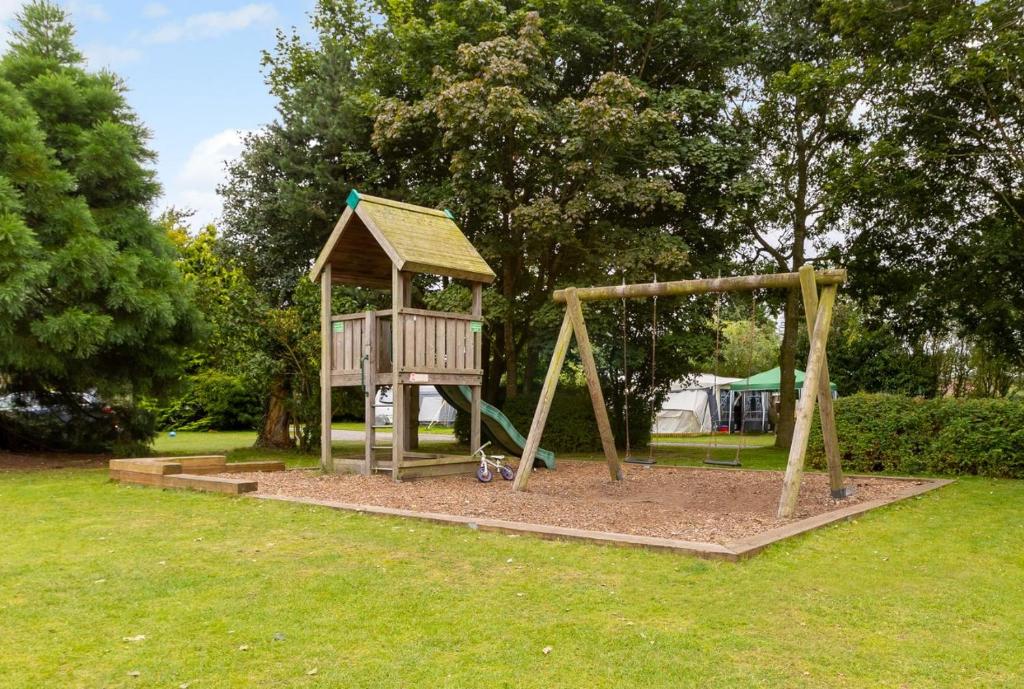 a playground in a park with a wooden swing at Luxury Luna in Whitchurch