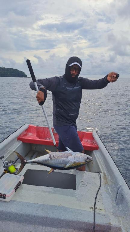 a man holding a spear and a fish on a boat at Alojamiento in Bahía Solano