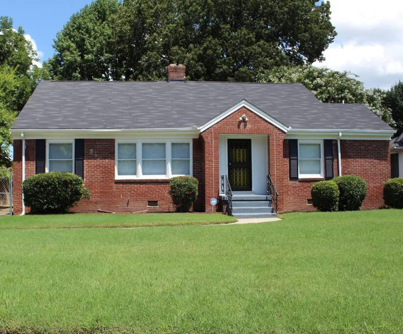 a red brick house with a black roof at 3BR, 2BA Hidden Gem in Midtown/Evergreen district in Memphis