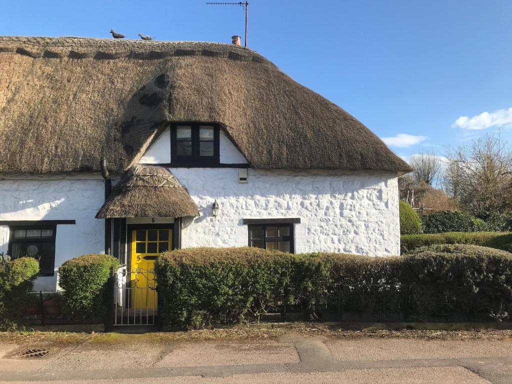 a thatch roofed house with a yellow door at 5 Packhorse in Swindon