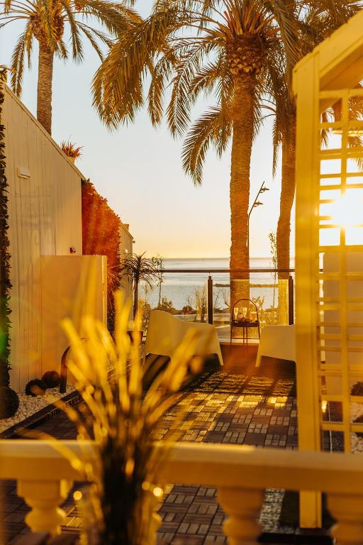 a patio with palm trees and a view of the ocean at HOSTAL LUXURY NIT I DIA in Altea
