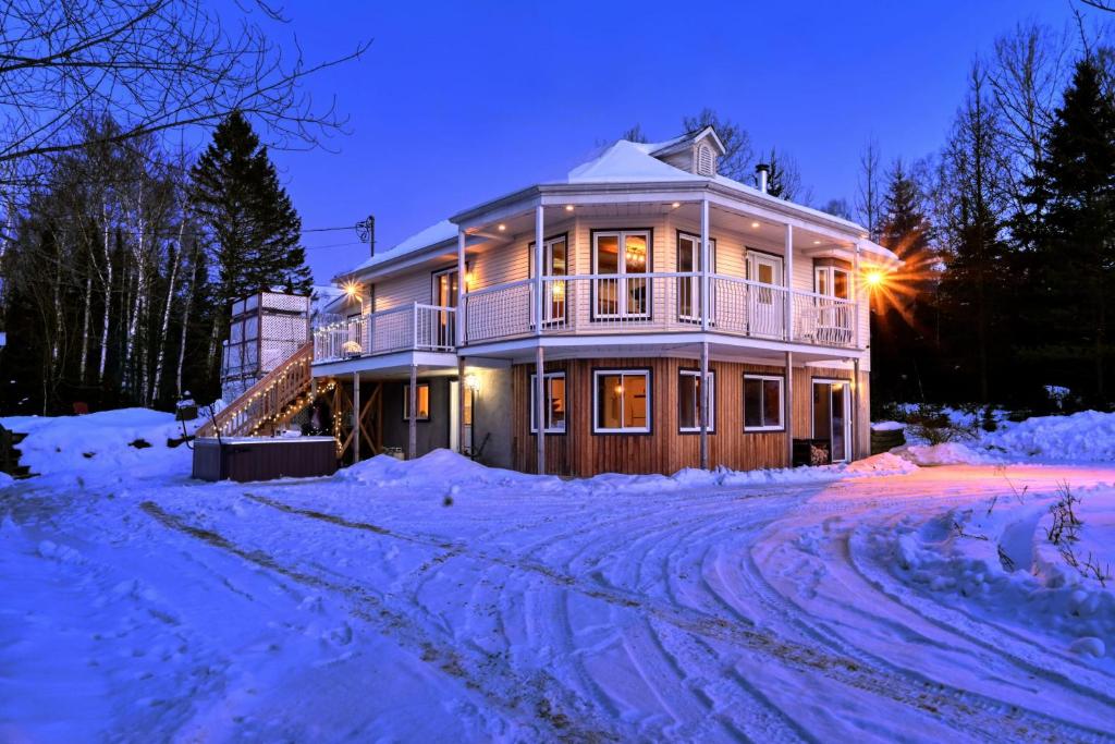 una casa grande en la nieve por la noche en Spacious cottage in forest with spa, en La Macaza