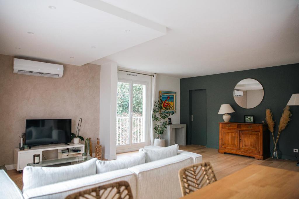 ein Wohnzimmer mit einem weißen Sofa und einem TV in der Unterkunft Appartement Résidence Villeneuve in Villeneuve-lès-Avignon