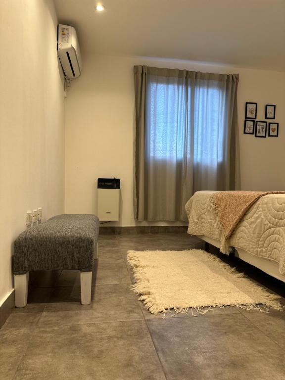 ein Schlafzimmer mit einem Bett und einem Stuhl und einem Fenster in der Unterkunft Departamentos amueblados Villanueva in Villa Mercedes