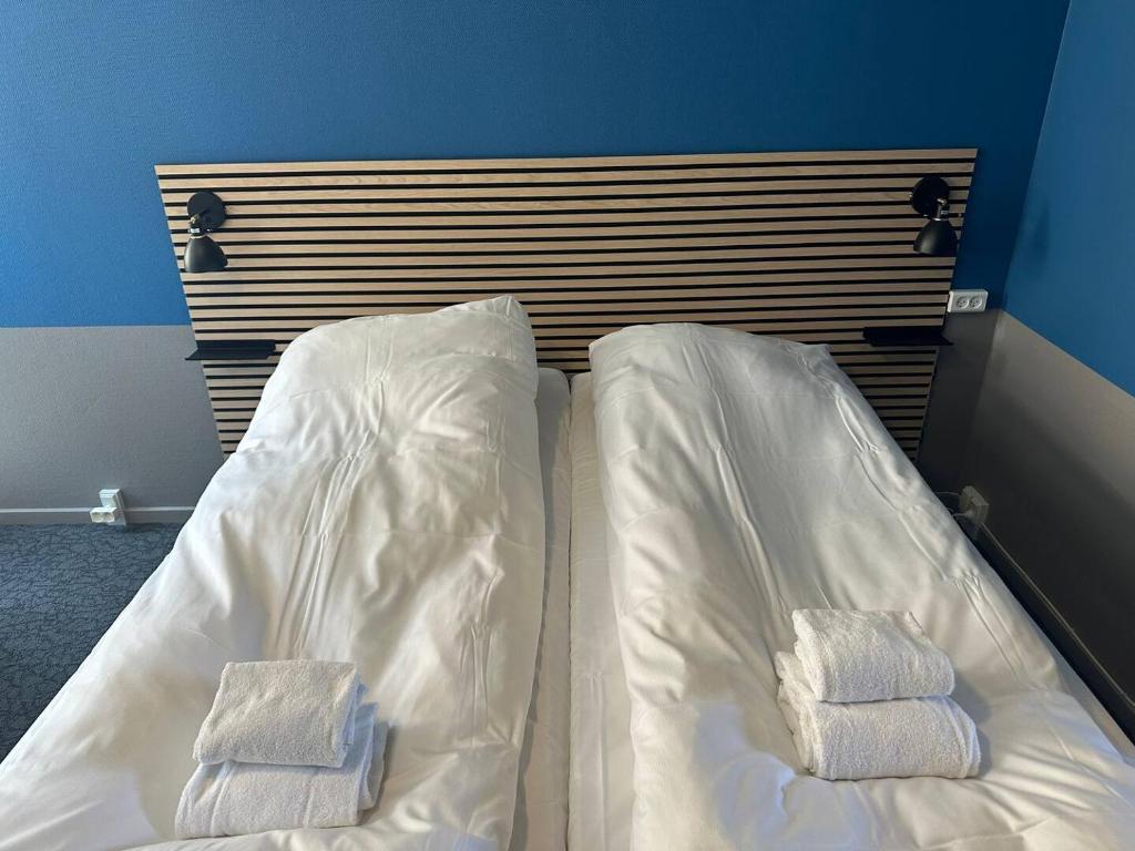 ein Bett mit weißer Bettwäsche und zwei Handtüchern darauf in der Unterkunft Room 8 On Pedestrian Street Sby - Free Parking in Sæby