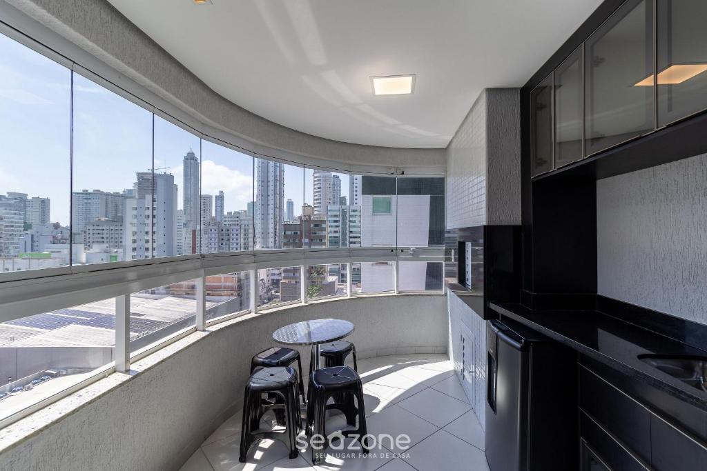 a kitchen with two stools and a table on a balcony at Apto c/ varanda 600m da orla Centro BC EJF0702 in Balneário Camboriú