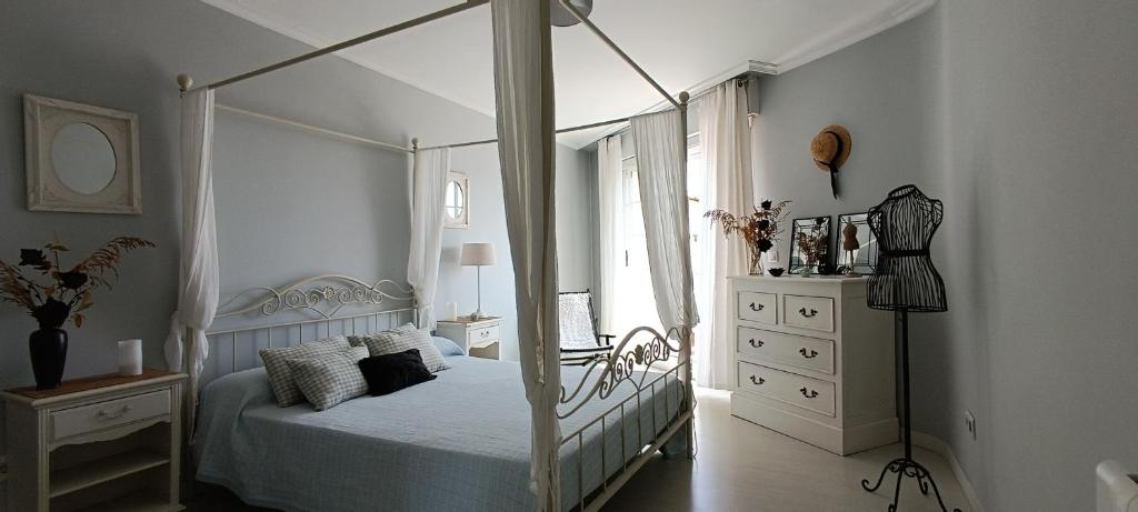 a white bedroom with a canopy bed and a dresser at Rincón del Mar Vacacional, Céntrico,Terrazas y Vistas a la Ría de Vigo in Moaña