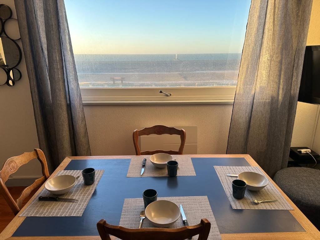 una mesa con vistas al océano desde una ventana en l'albatros "le pont", en Cayeux-sur-Mer