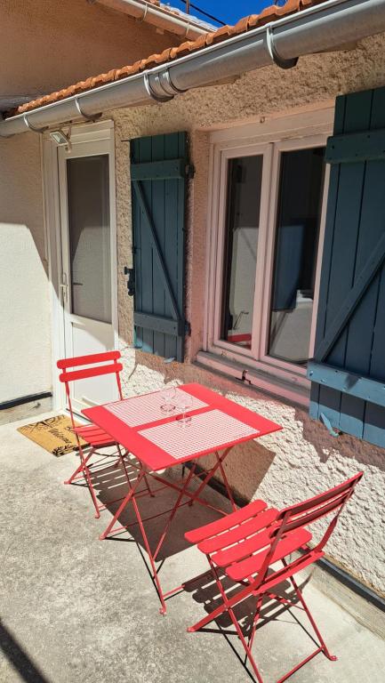 Deux chaises rouges et une table en face d'un bâtiment dans l'établissement Ancien appartement de pêcheur, à Toulon
