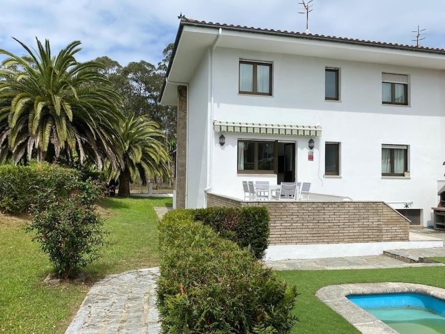 a white house with a swimming pool in front of it at La Casina de Rodiles in Liñero