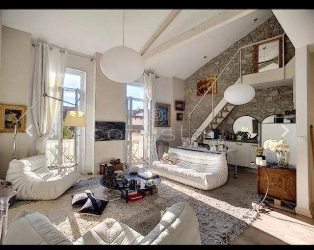 Elle comprend un salon doté d'un mobilier blanc et d'un mur en pierre. dans l'établissement CANNES DUPLEX CROISETTE FESTIVAL 5 et 6 VOYAGEURS, à Cannes
